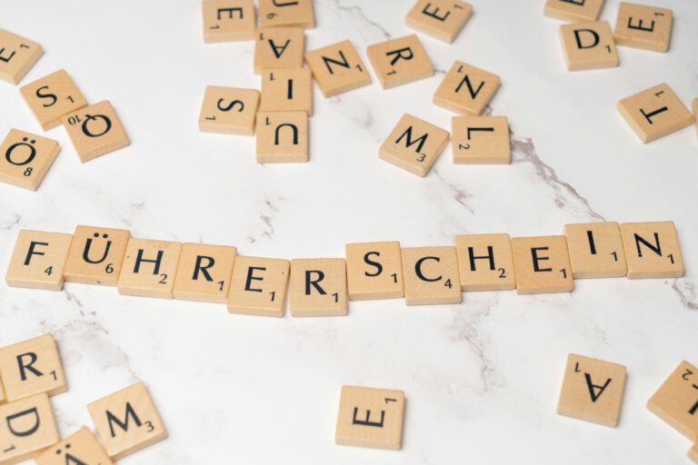 Scrabble tiles arranged to spell 'Führerschein' on a marble surface, representing language and word games.